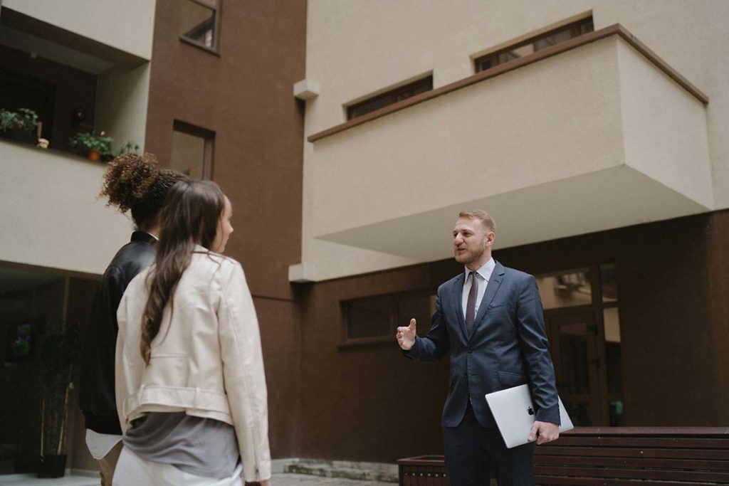 People standing with a real estate agent in front of a building