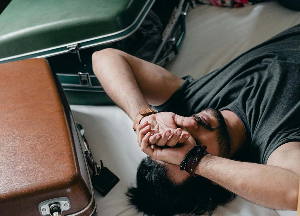 Man lying on a bed with suitcases